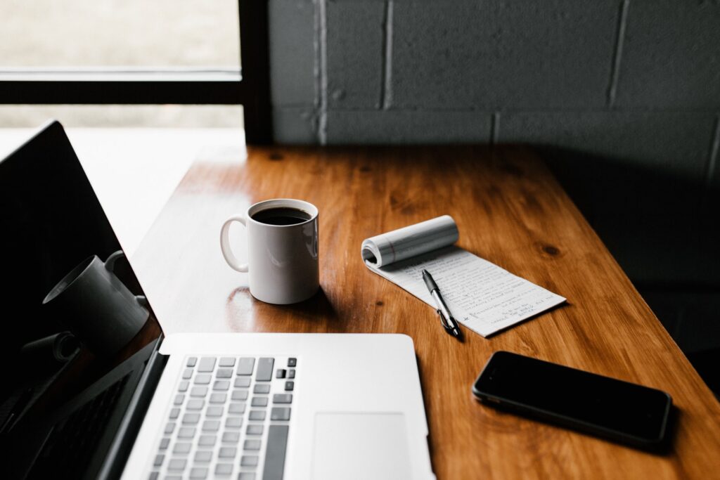 a desk with a laptop and a phone and a cup of coffee