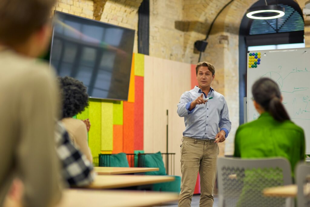 a man in a boardroom talking to his team as they do fast team building activities meant for boosting communication