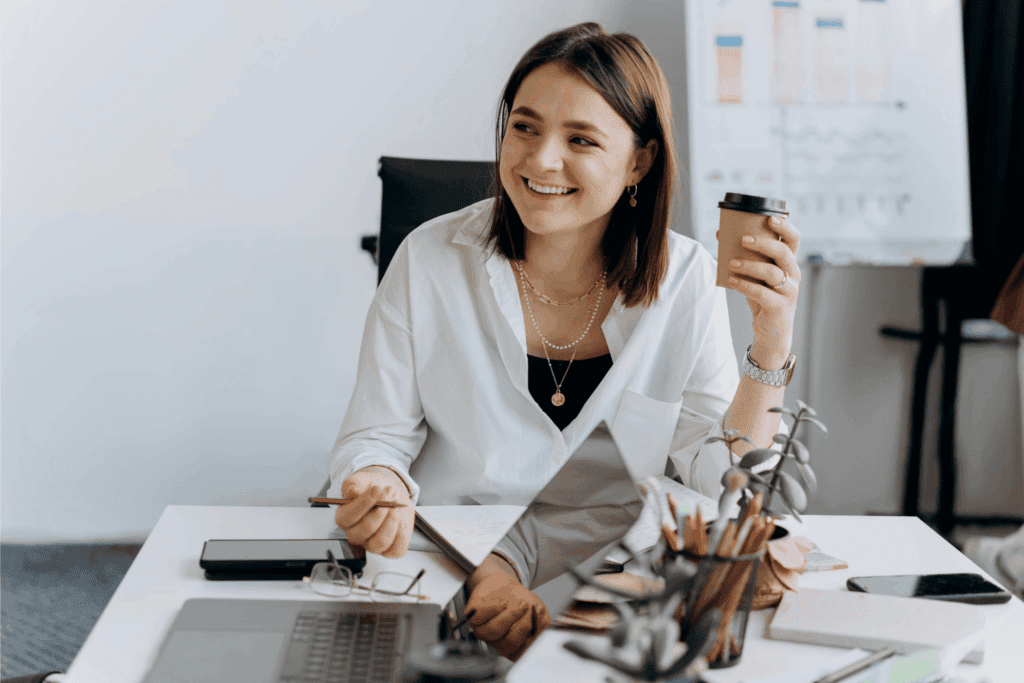 Woman smiling at her desk holding a coffee