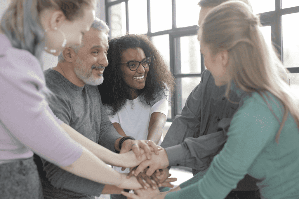 A diverse team of professionals joins hands in a show of unity and collaboration