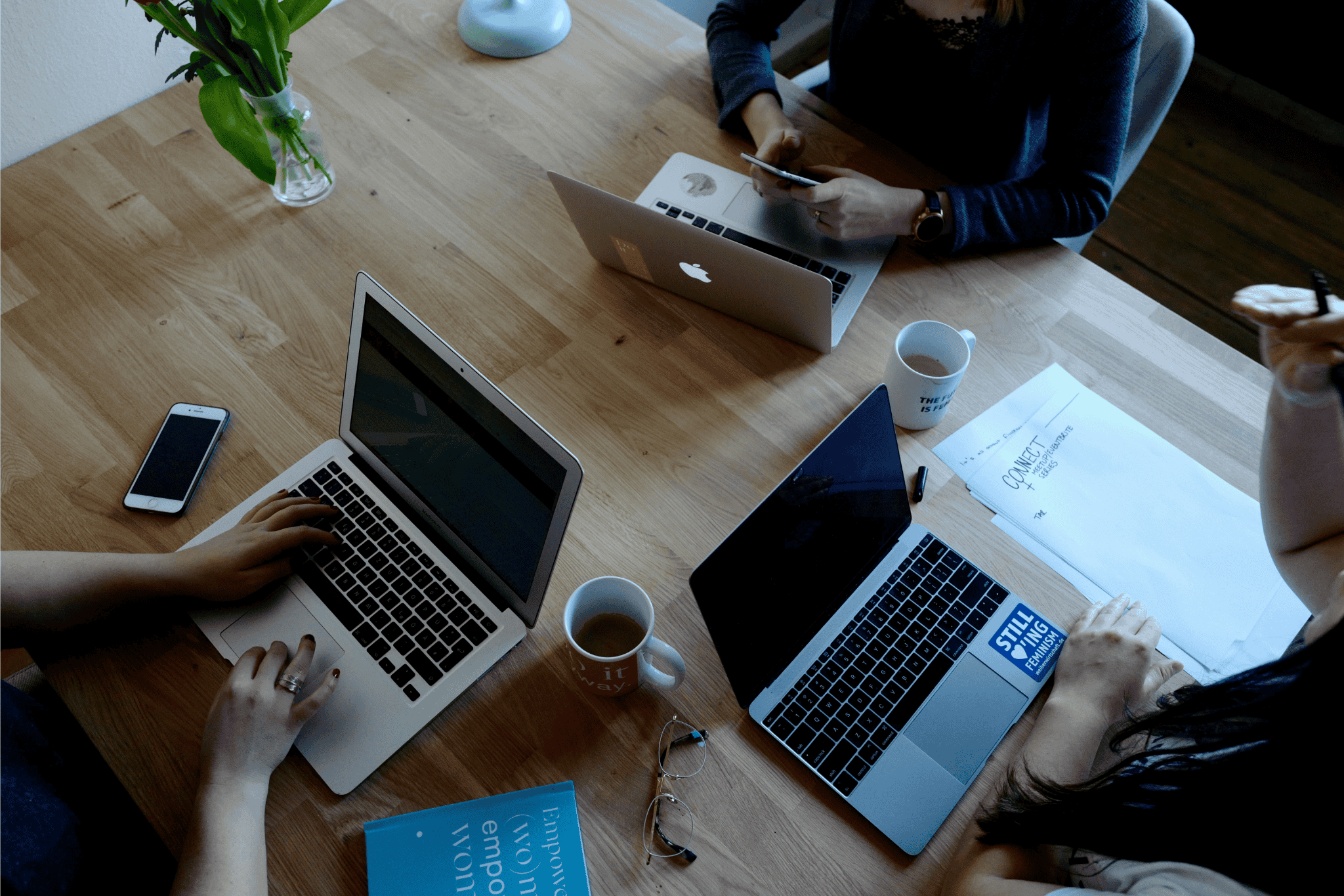 Overhead view of collaborative team workspace with laptops, coffee, and notes