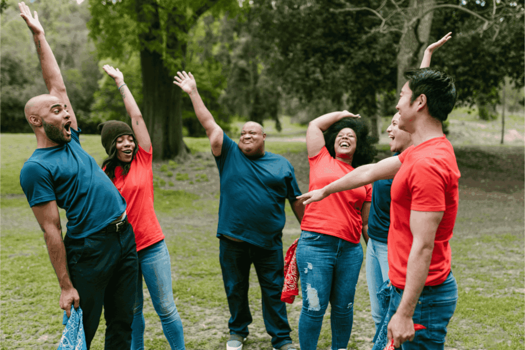 Group of adults celebrating outdoors during a team-building activity – corporate retreat, employee engagement, teamwork, and group bonding