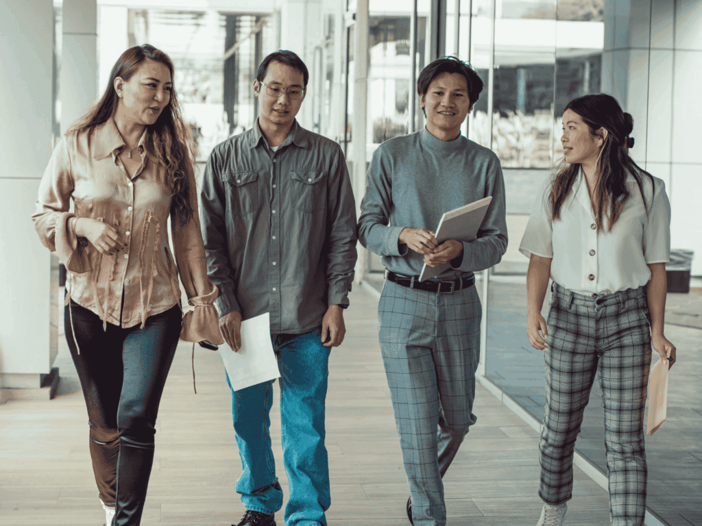 Diverse team of young professionals walking through a modern office corridor during a collaborative workday