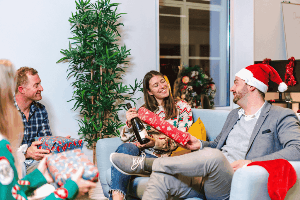Coworkers exchanging gifts and enjoying festive cheer during a lively office holiday party.