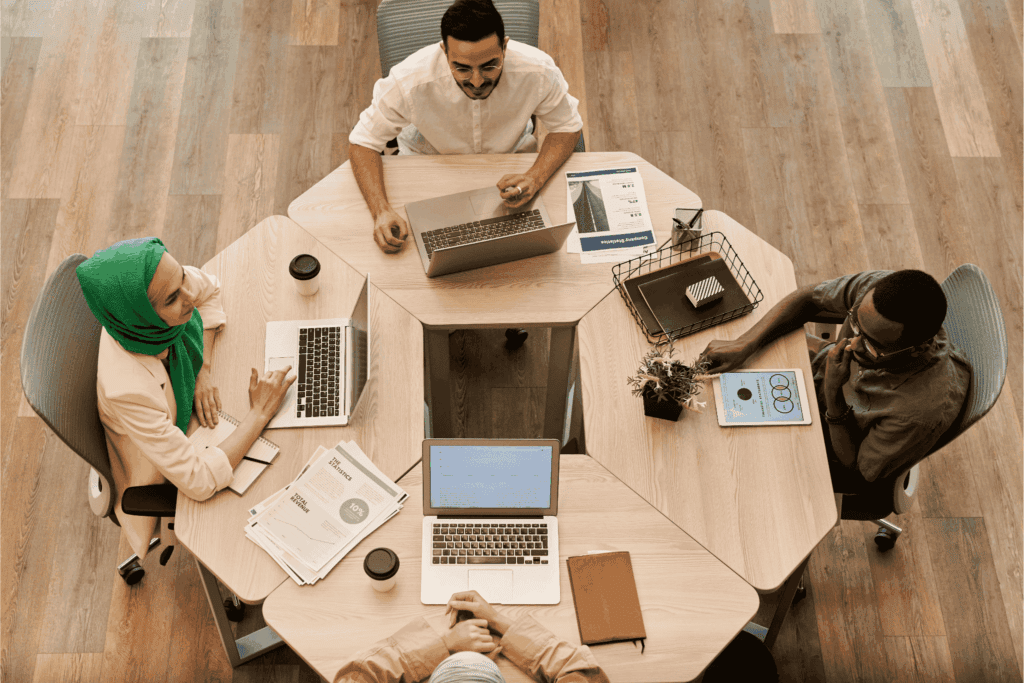 team collaborates in a modern office space, working on laptops and tablets during a business meeting