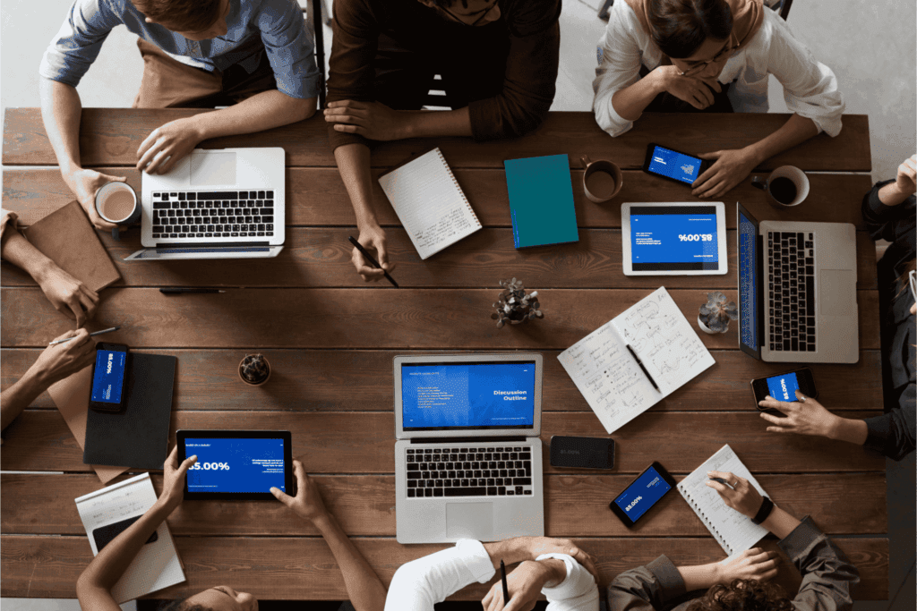 Birds eye view of a busy communal work desk during a team meeting