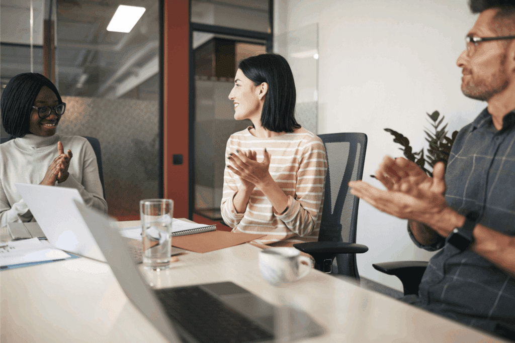 Coworkers applauding a new team member during an onboarding session, celebrating their introduction in a supportive office environment.
