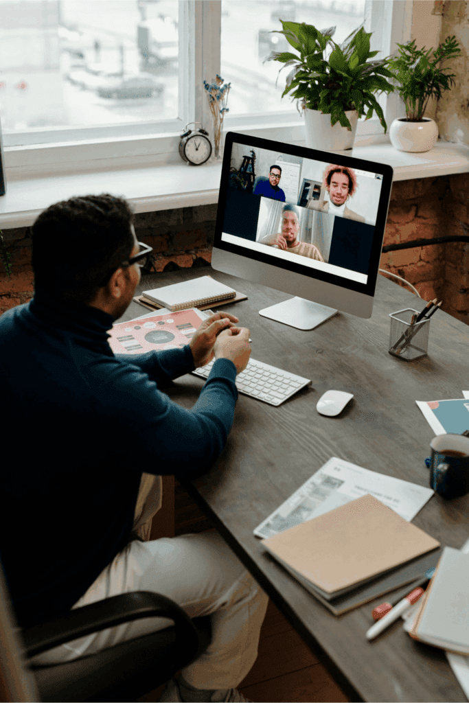Professional participating in a virtual team meeting on a desktop computer, collaborating with colleagues remotely from a home office