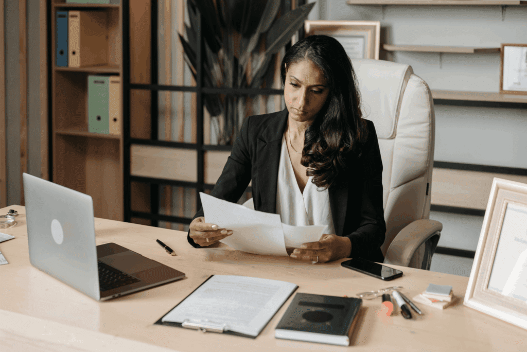 A business professional reviews employee package documents at her desk.
