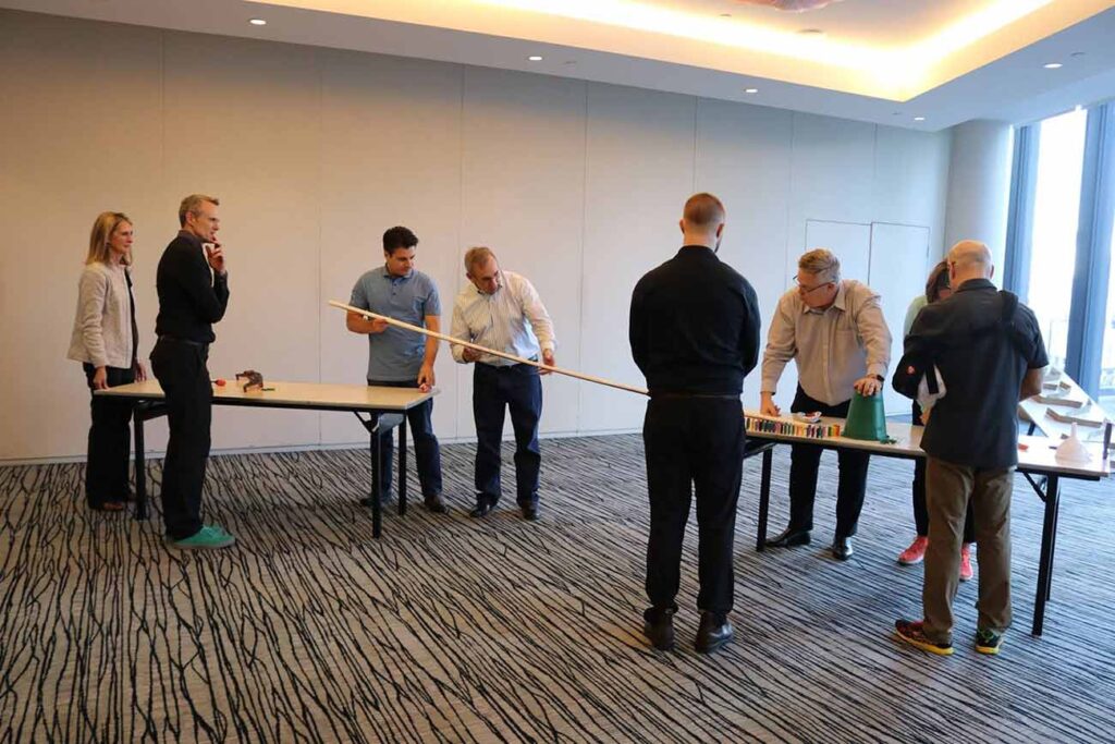 a senior leadership team taking part in a domino effect challenge team building activity