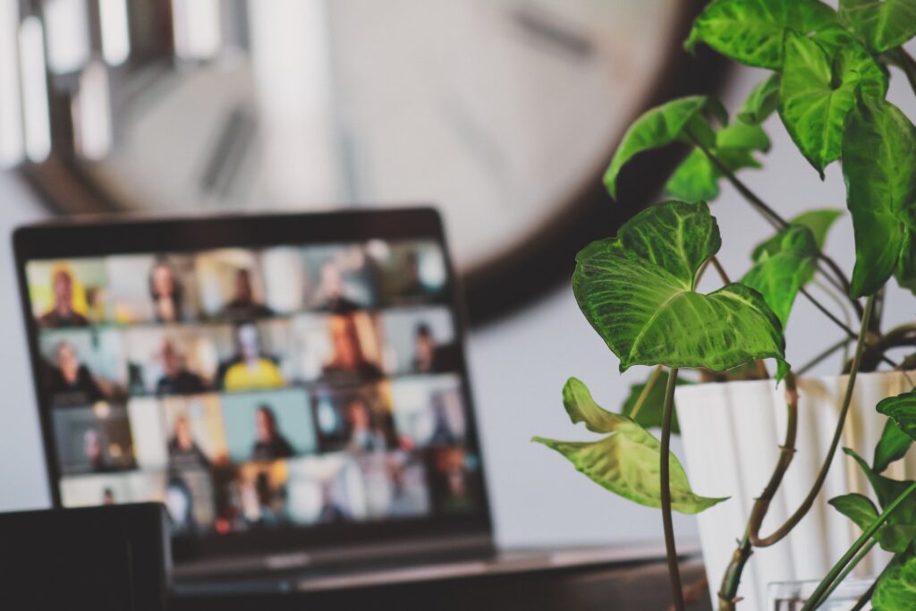 a computer in a home office with a screen filled with colleagues 