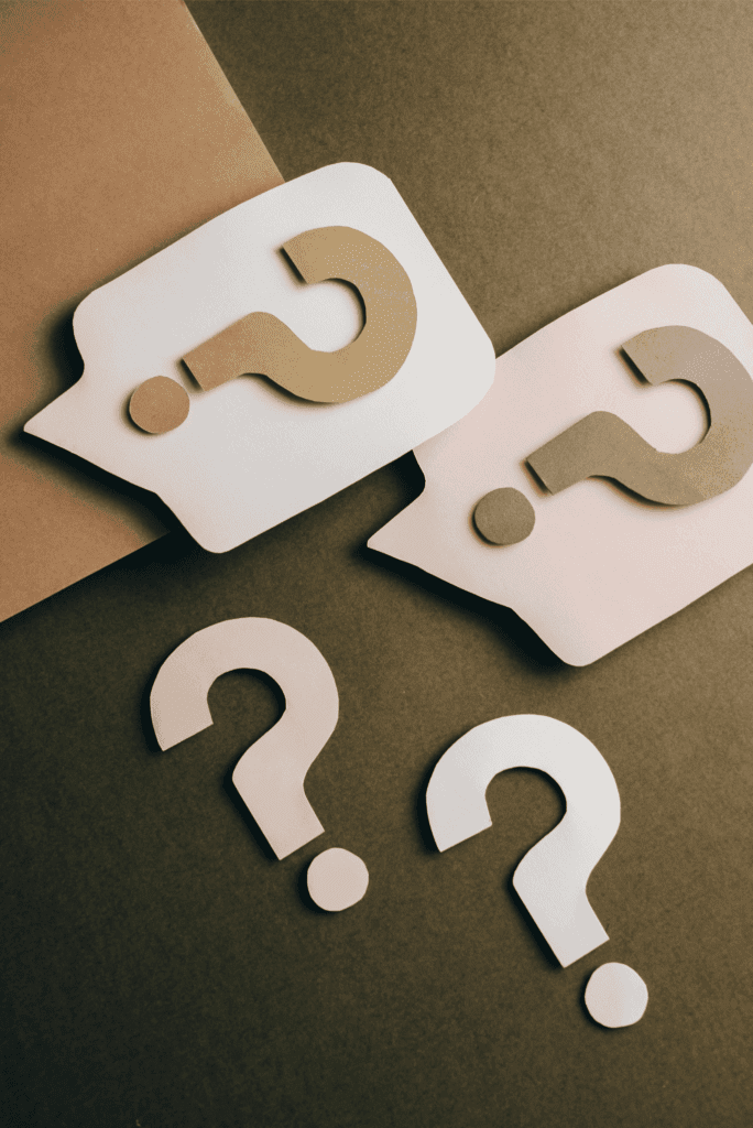 Paper cut-out question marks and speech bubbles symbolizing curiosity, doubt, and problem-solving