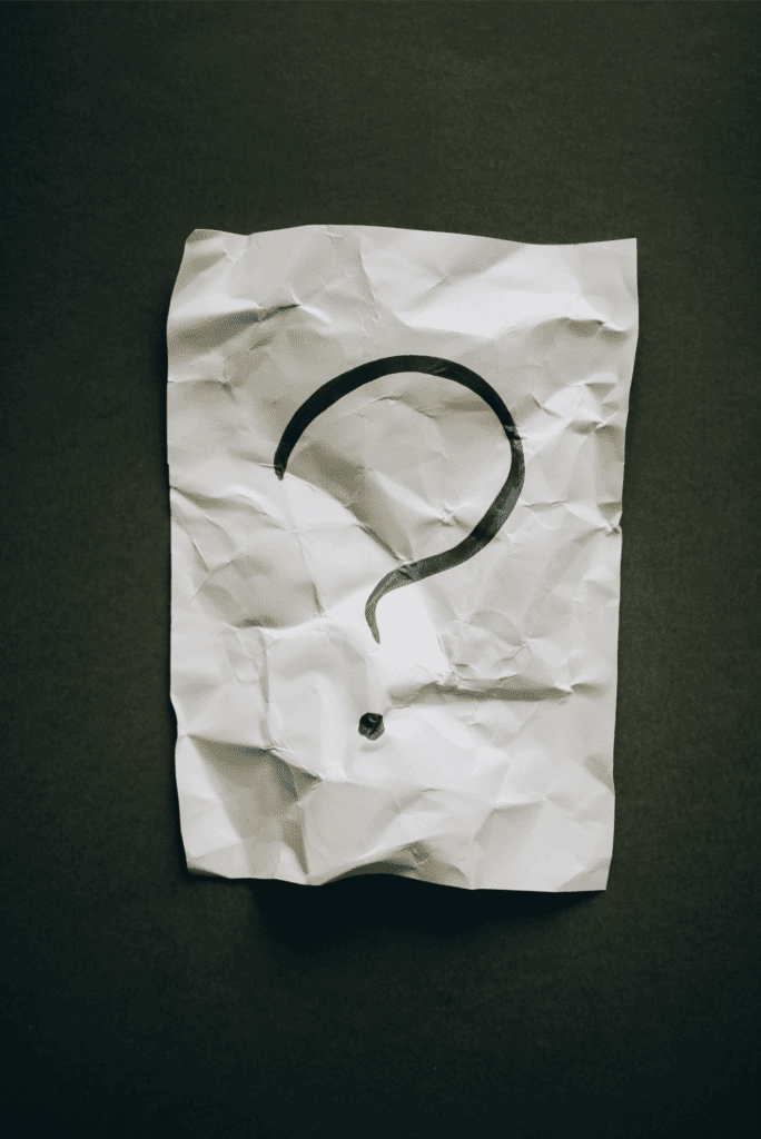 Crumpled up piece of paper with a bold, black question mark written in marker