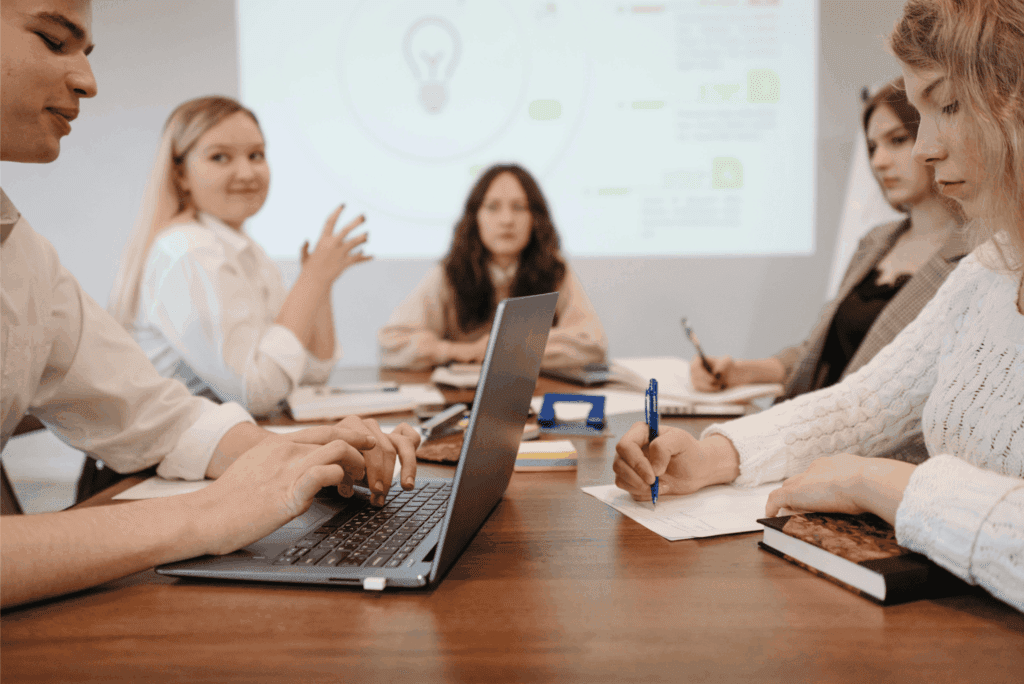 Corporate team engaged in a business meeting with laptops, notes, and collaboration in a modern office setting.