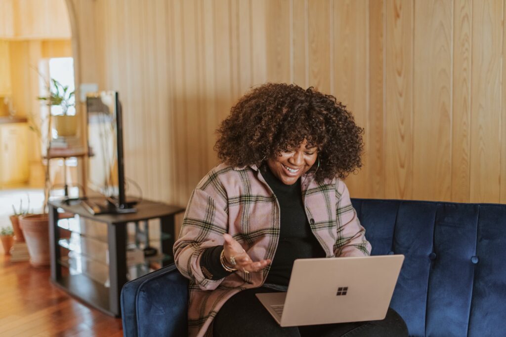 a happy and productive employee sitting on the couch at her office smiling at her computer