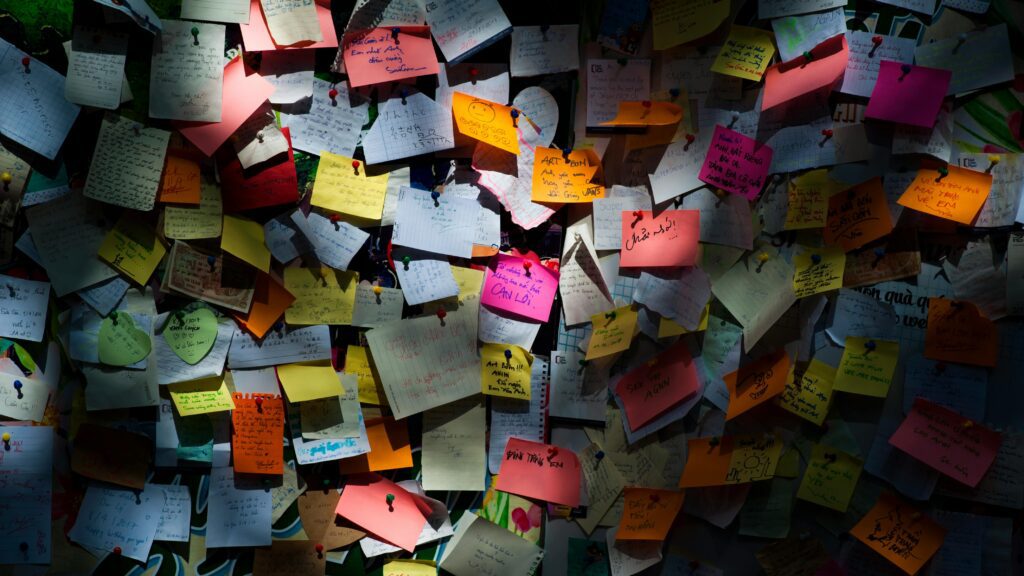 Colorful sticky notes and handwritten messages pinned on a crowded wall – brainstorming, creativity, and idea board concept.