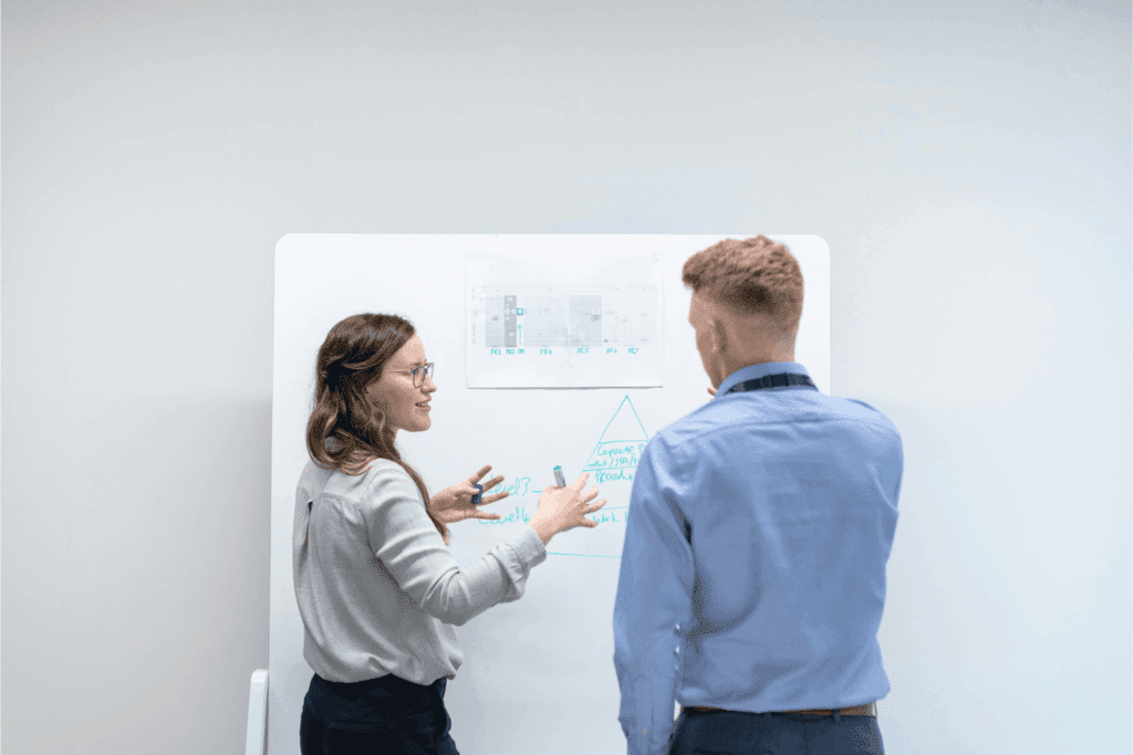 Two business professionals collaborating at a whiteboard with charts and diagrams – teamwork, strategy, and office productivity concept.