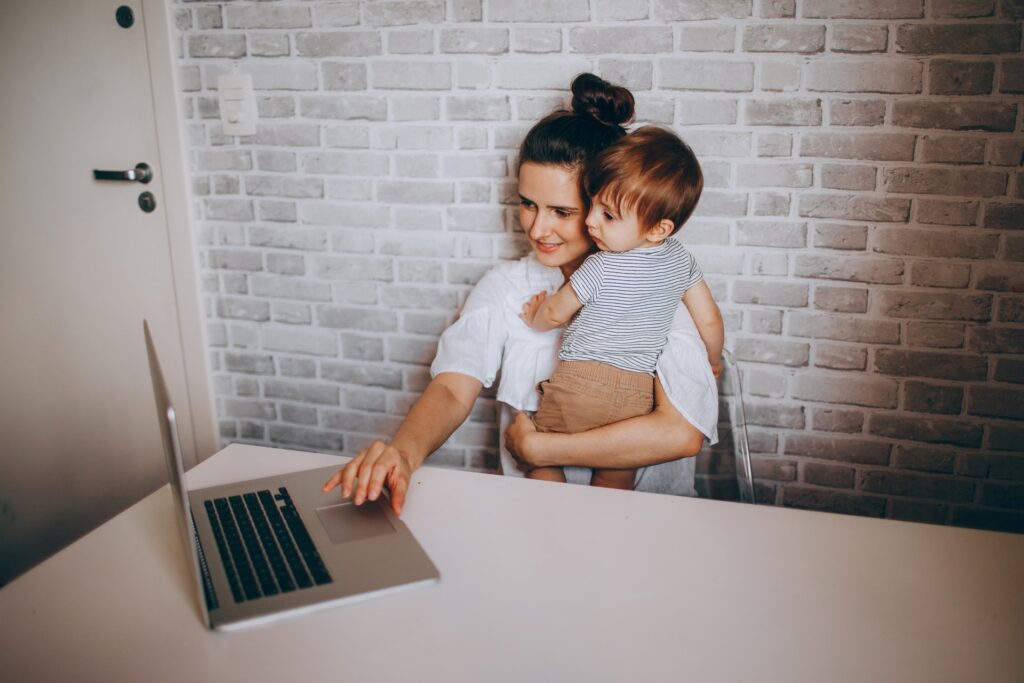 a remote employee working from home while holding her child