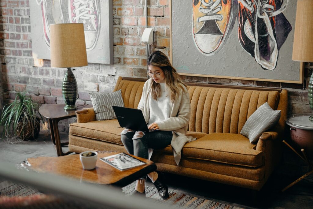 a woman working remotely sitting on a couch on her laptop
