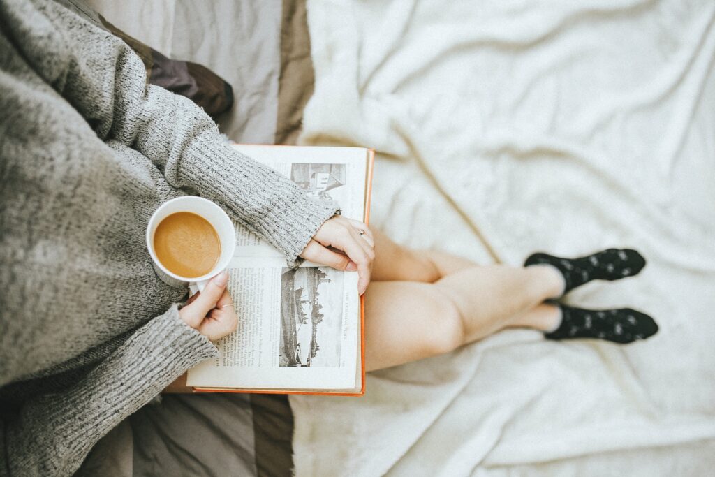a woman sitting with a vbook and a cup of coffee on her afternoon off