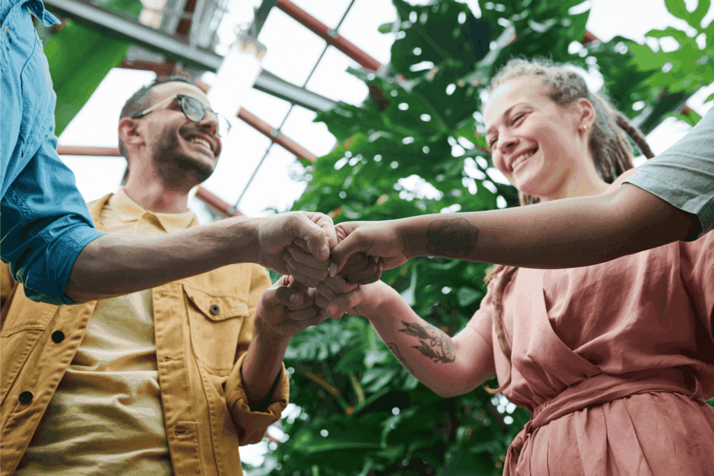 Smiling group of people doing a fist bump – teamwork, collaboration, and community success concept.
