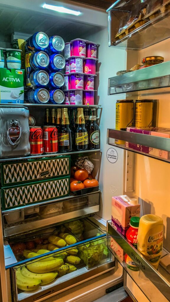 Open refrigerator stocked with drinks, yogurt, fruits, and fresh produce – healthy lifestyle, groceries, and food storage concept.
