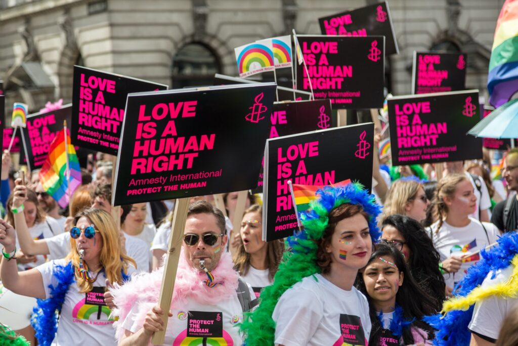 a group of people celebrating and holding signs at their local pride parade for pride month at work