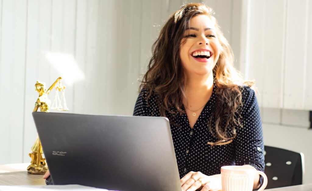 a happy and engaged employee sitting at her desk with her computer and smiling