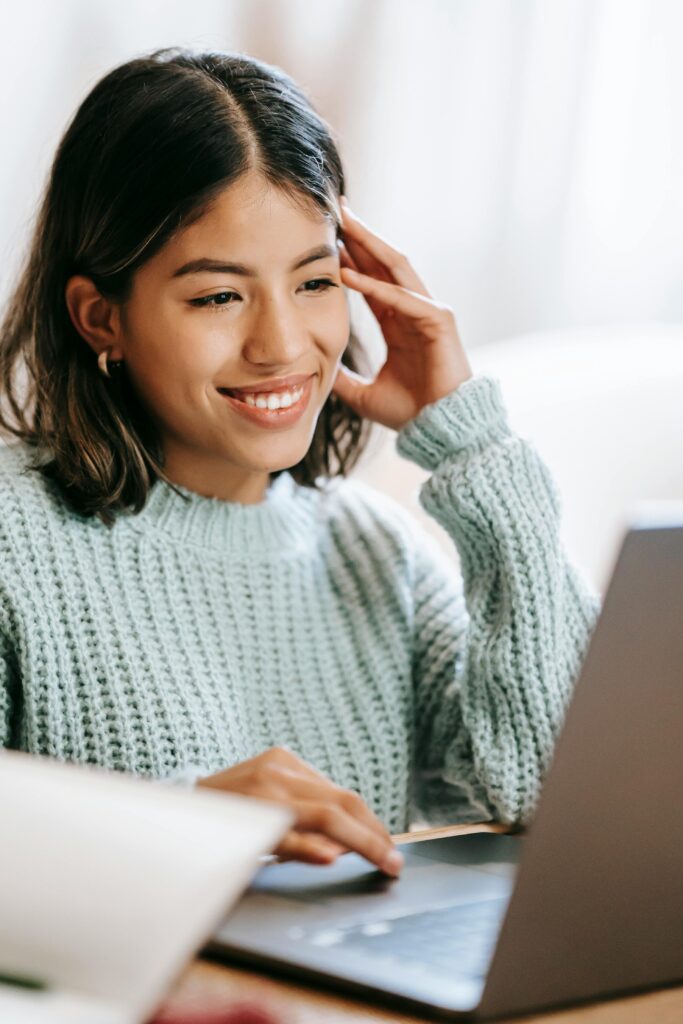 Smiling young woman working on a laptop at home – remote work, online learning, and digital lifestyle concept.