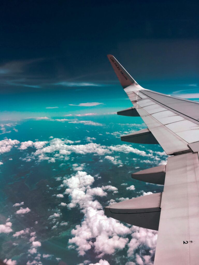 Airplane wing view from the window flying above clouds – travel, aviation, and adventure in the sky concept.