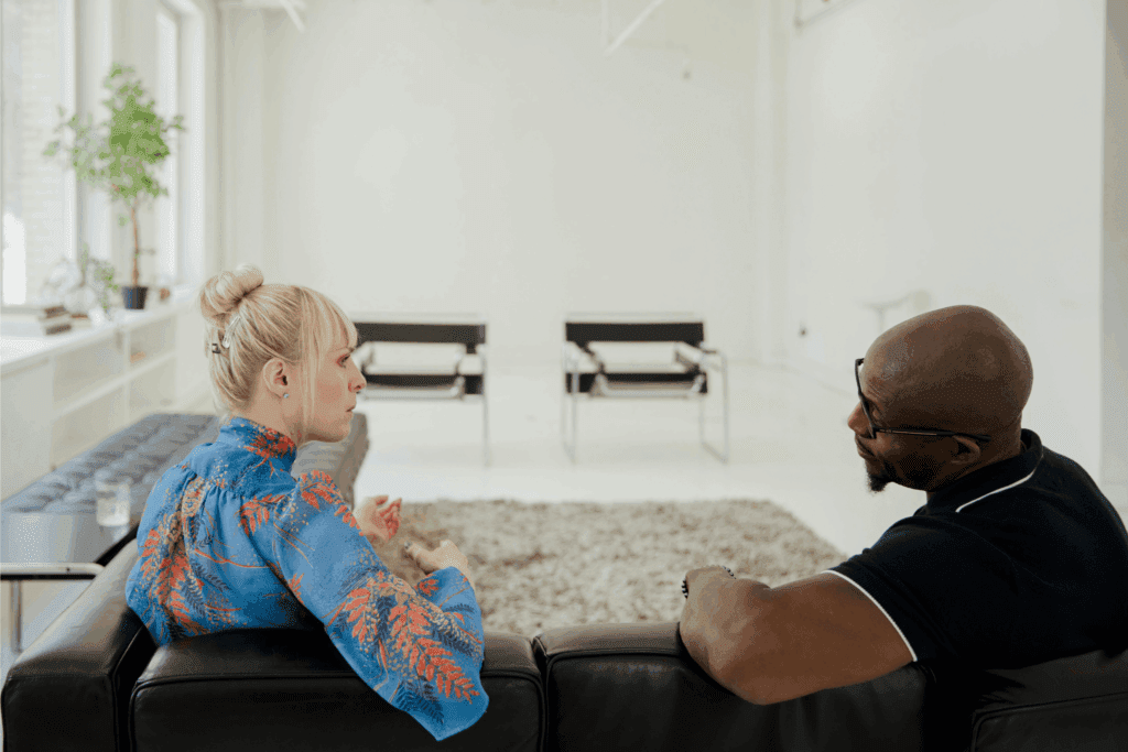 Two colleagues sitting on a couch engaged in conversation – professional feedback session and constructive communication concept