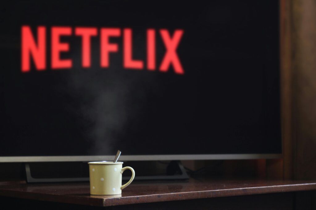 Cozy setup with a steaming cup of coffee in front of a TV screen displaying the Netflix logo.