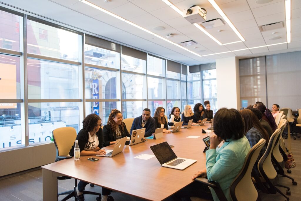 a large sales team gathered around a boardroom in their office 
