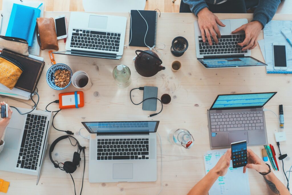 a number of people stting at a desk with various types of technology