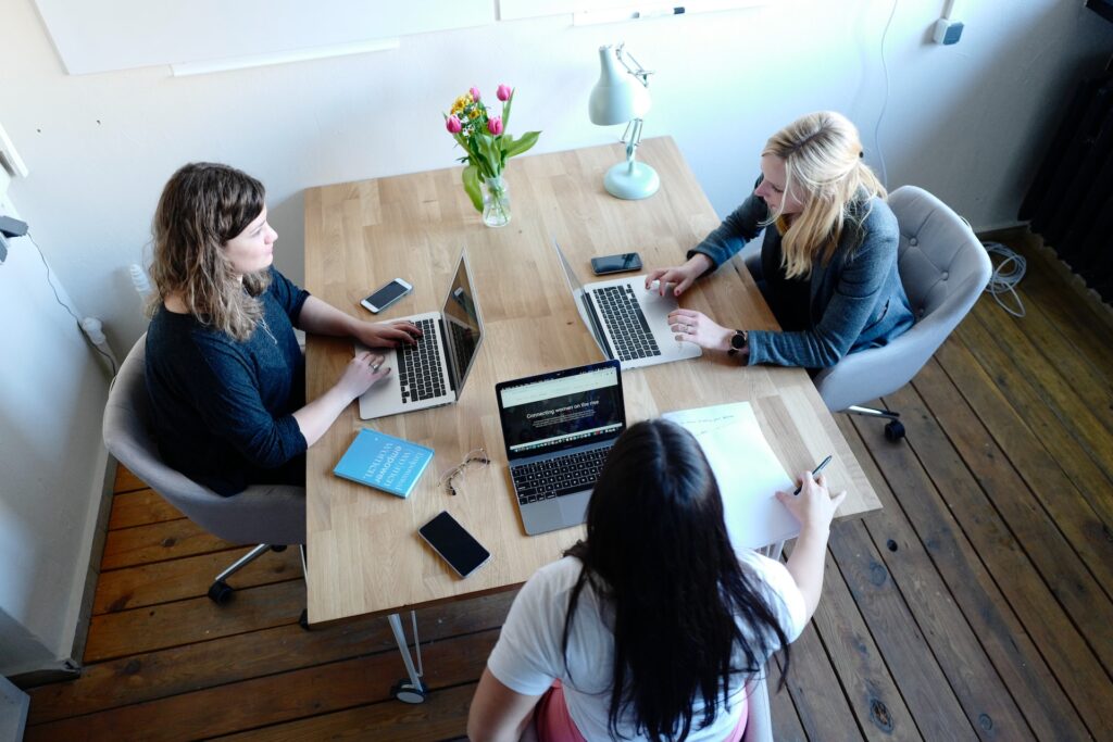 three women on a hybrid team working at a desk together