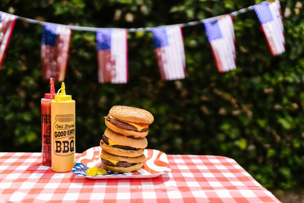 Stacked cheeseburgers with ketchup and mustard sit on a patriotic plate, perfect for a July 4th BBQ.