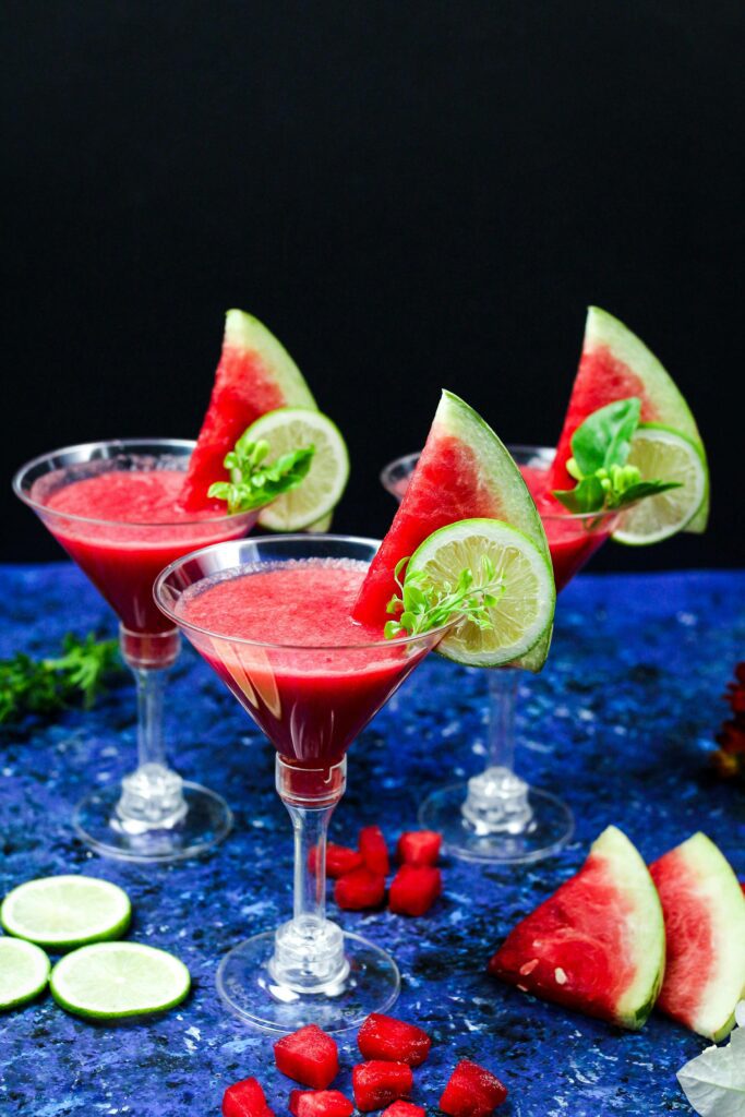 Festive watermelon cocktails garnished with lime and basil, perfect for refreshing July 4th celebrations.