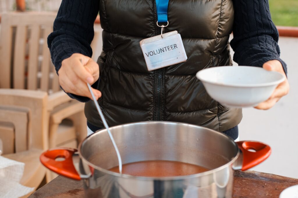 a woman with a volunteer nametag pouring soup into a bowl