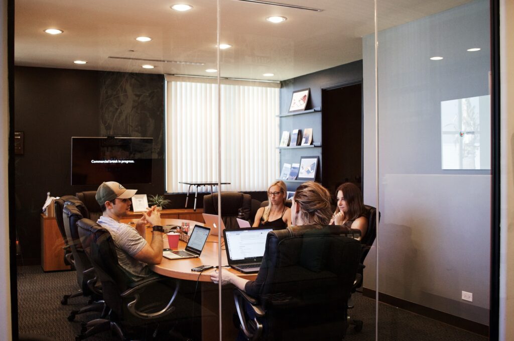 a group of colleagues in a conference room doing a remote hosted team building activity between meetings
