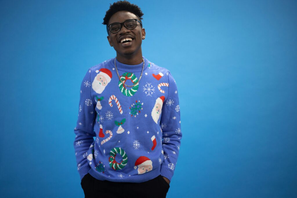 Man smiling in festive Christmas sweater with Santa and holiday patterns