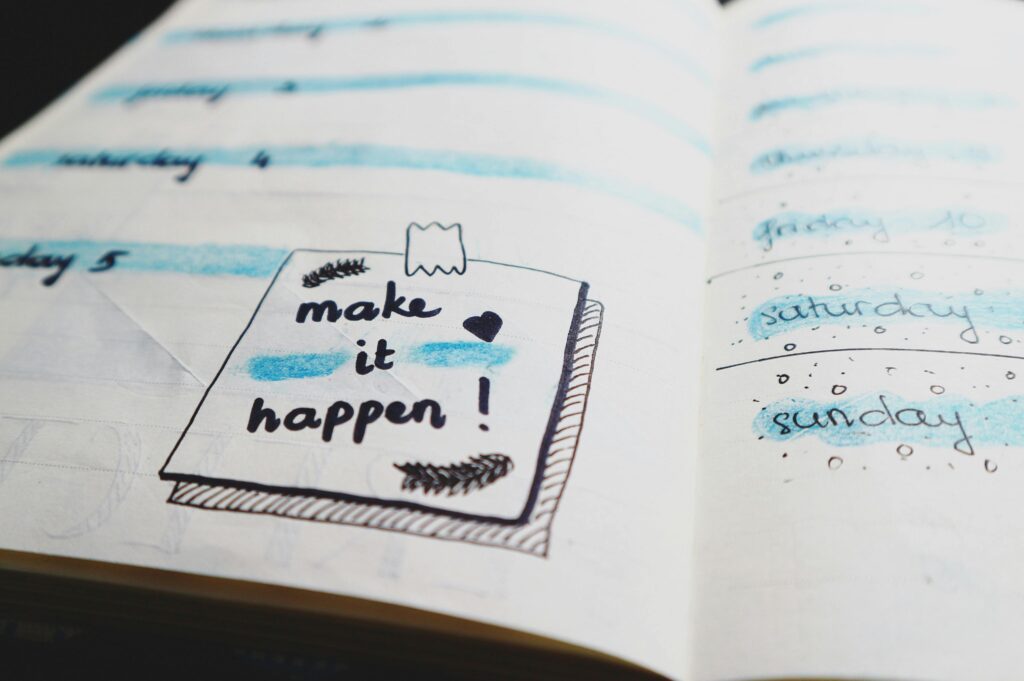 Motivational planner with handwritten note saying make it happen for goal setting and productivity planning.