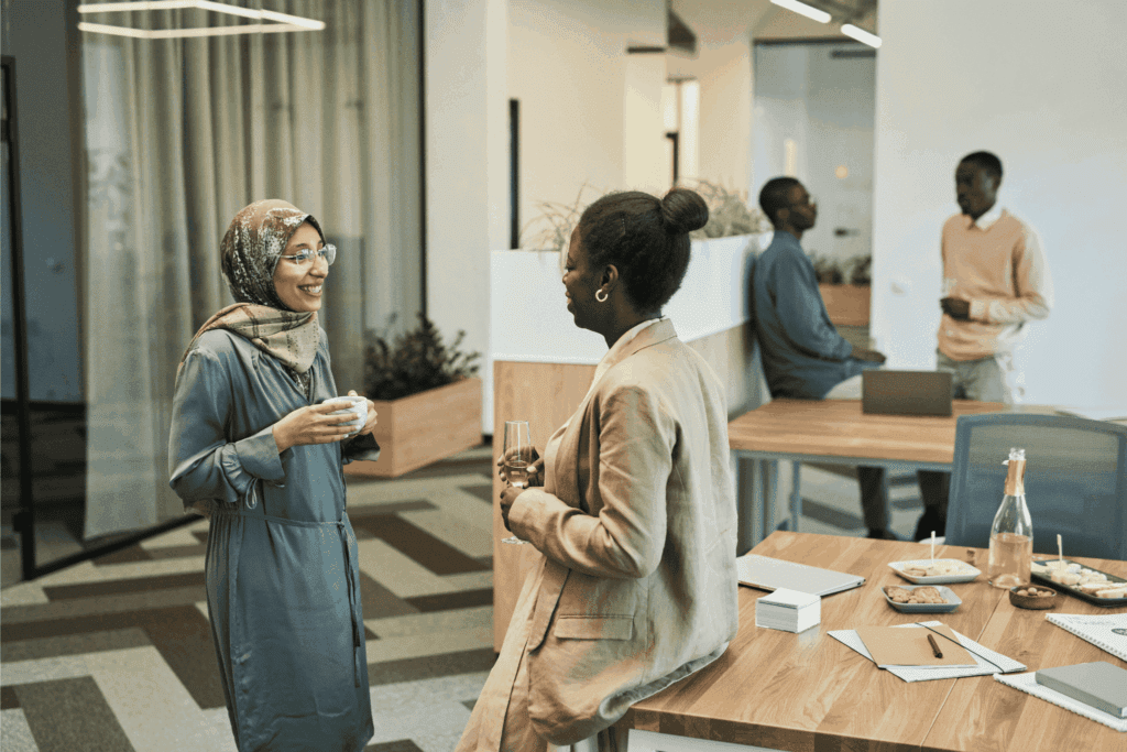 Employees networking and having casual conversations during an office break with drinks and snacks.