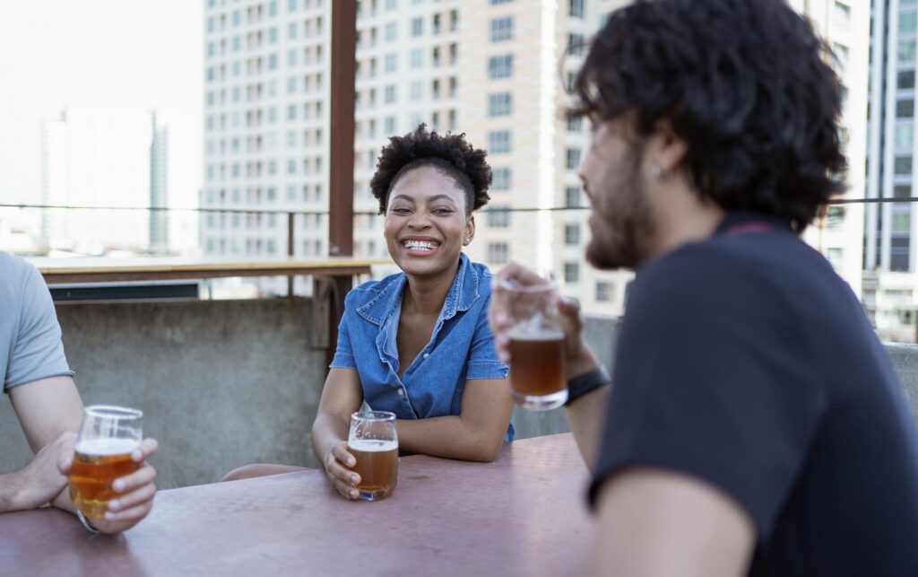 Friends enjoying craft beer together on a rooftop patio in the city.
