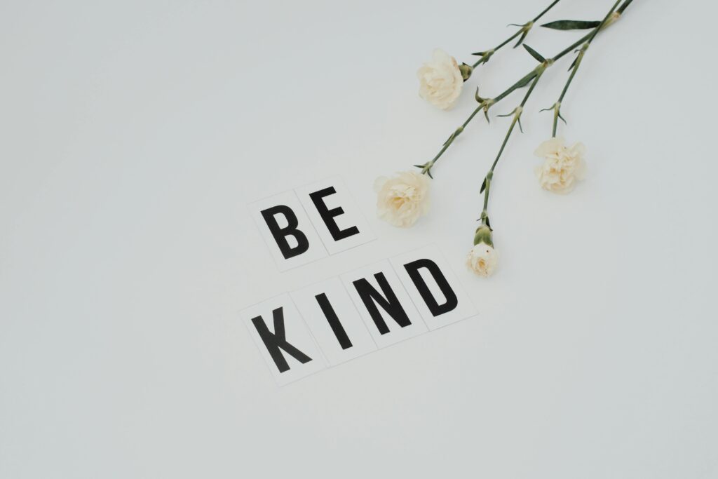 Inspirational message be kind with white flowers on minimal background