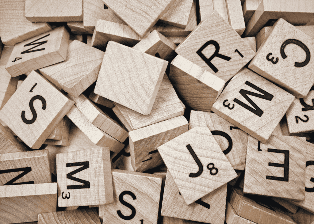 Pile of wooden Scrabble tiles with black letters and point values