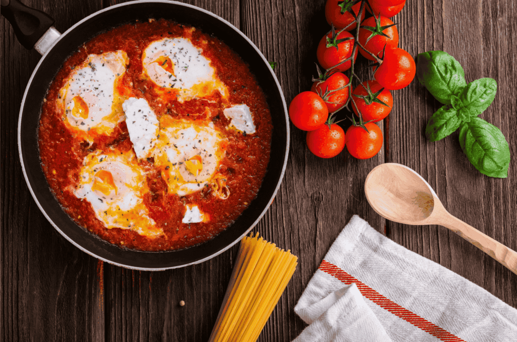 Shakshuka with poached eggs in a rich tomato sauce, garnished with herbs and fresh basil