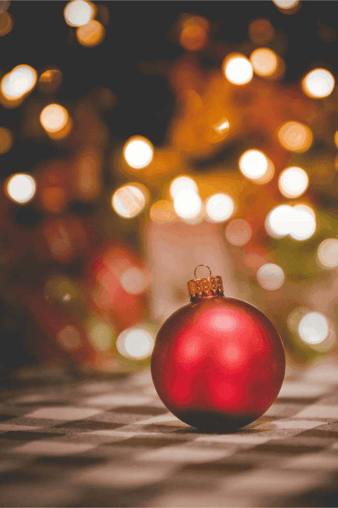 Red Christmas ornament with festive holiday lights in the background