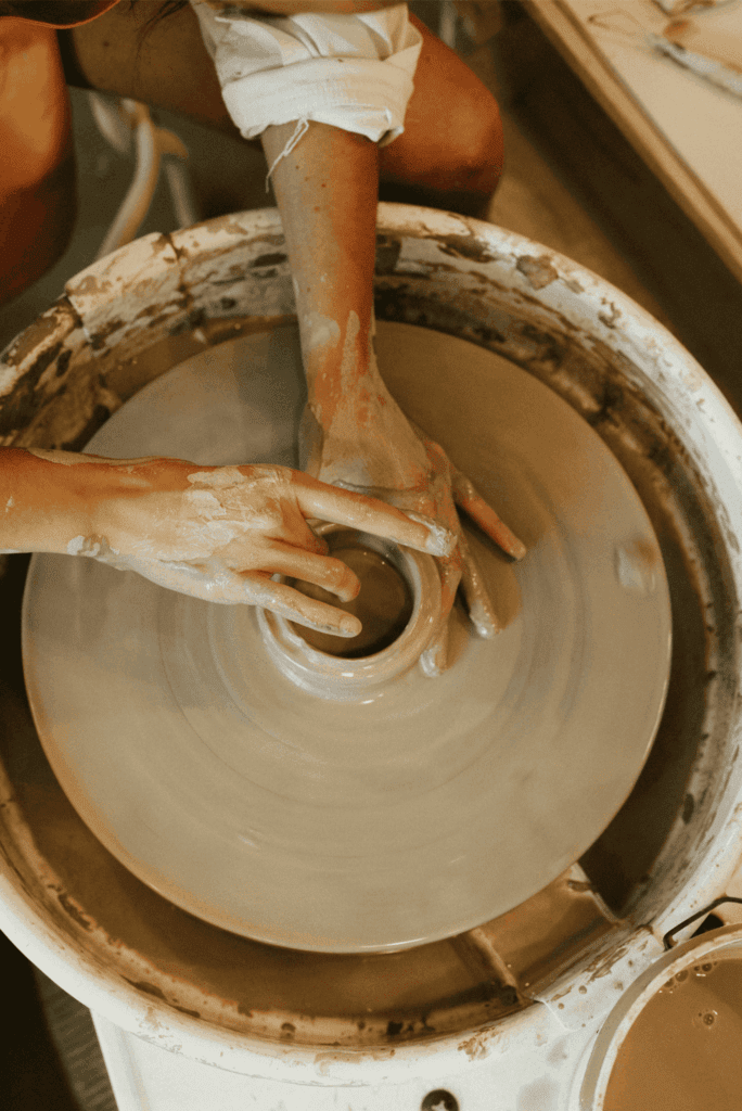 Hands shaping clay on a pottery wheel during a ceramic art workshop