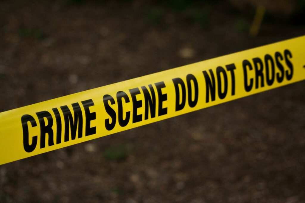 Close-up of yellow crime scene tape with bold black text reading 'CRIME SCENE DO NOT CROSS,' marking off a restricted investigation area