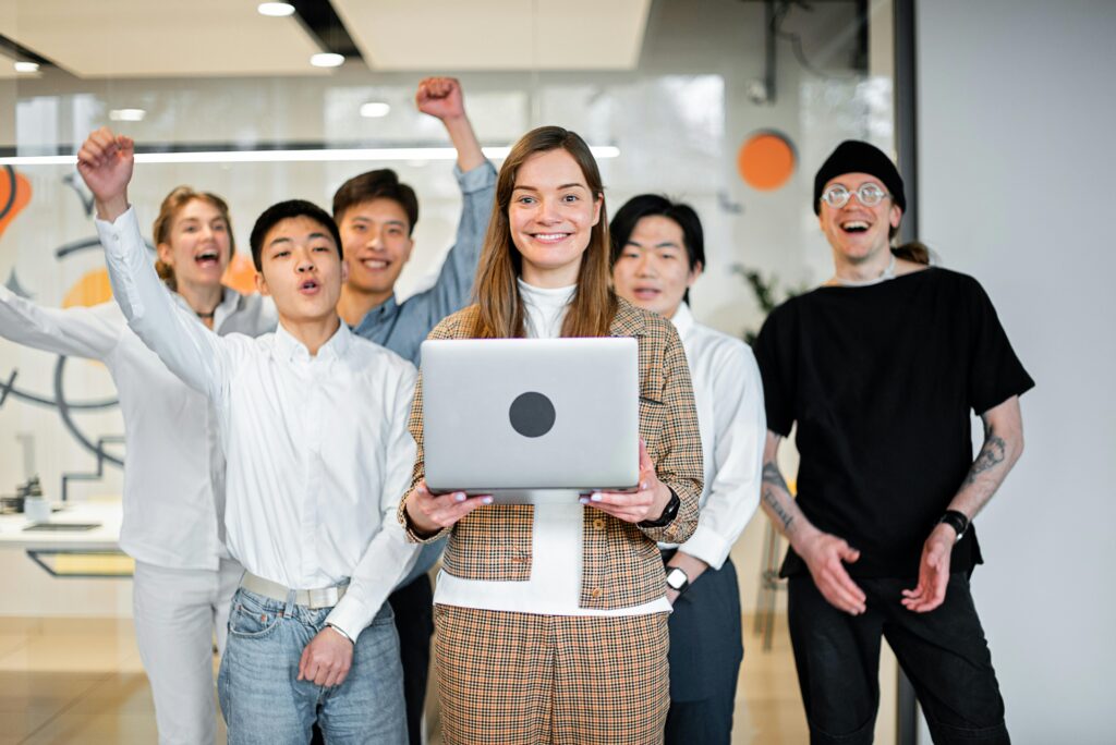 Smiling business team celebrating success with a laptop in a modern office setting